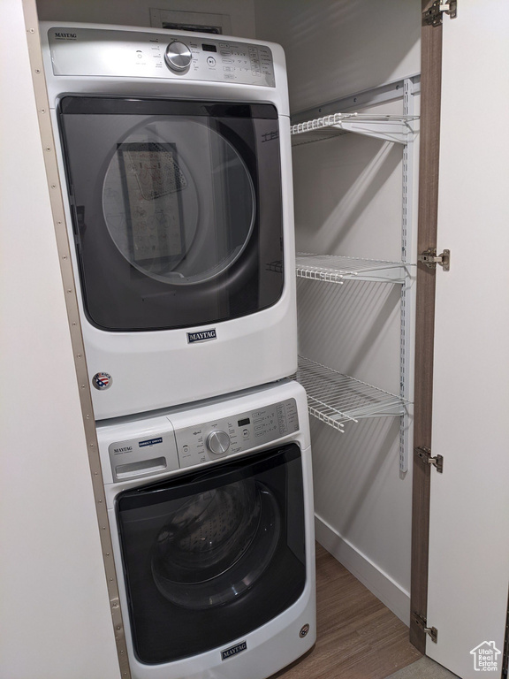 Laundry area with hardwood / wood-style floors and stacked washer / dryer