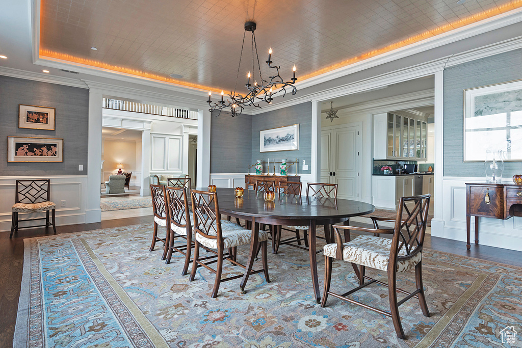 Dining space featuring hardwood / wood-style floors, a raised ceiling, and a chandelier