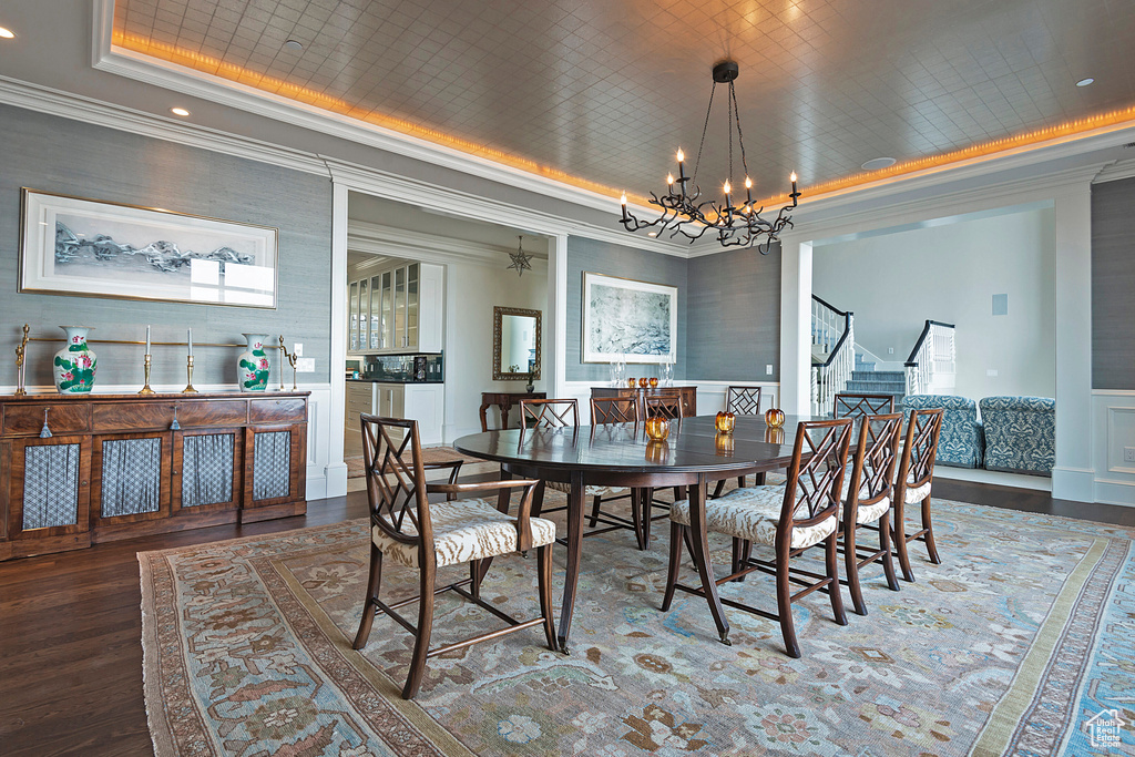 Dining room with a chandelier, a tray ceiling, crown molding, and hardwood / wood-style flooring