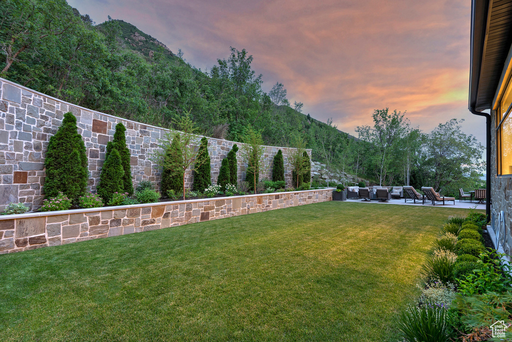 Yard at dusk featuring a patio area, an outdoor living space, and a mountain view