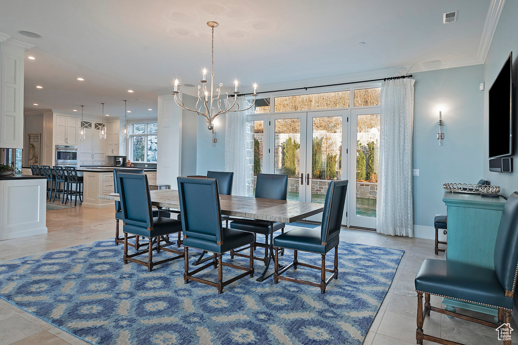 Dining room featuring french doors, crown molding, light tile flooring, and a chandelier