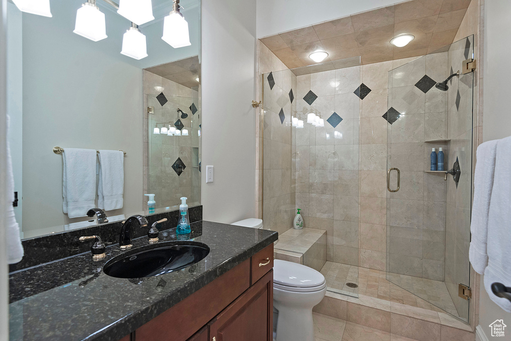 Bathroom featuring tile flooring, walk in shower, oversized vanity, and toilet