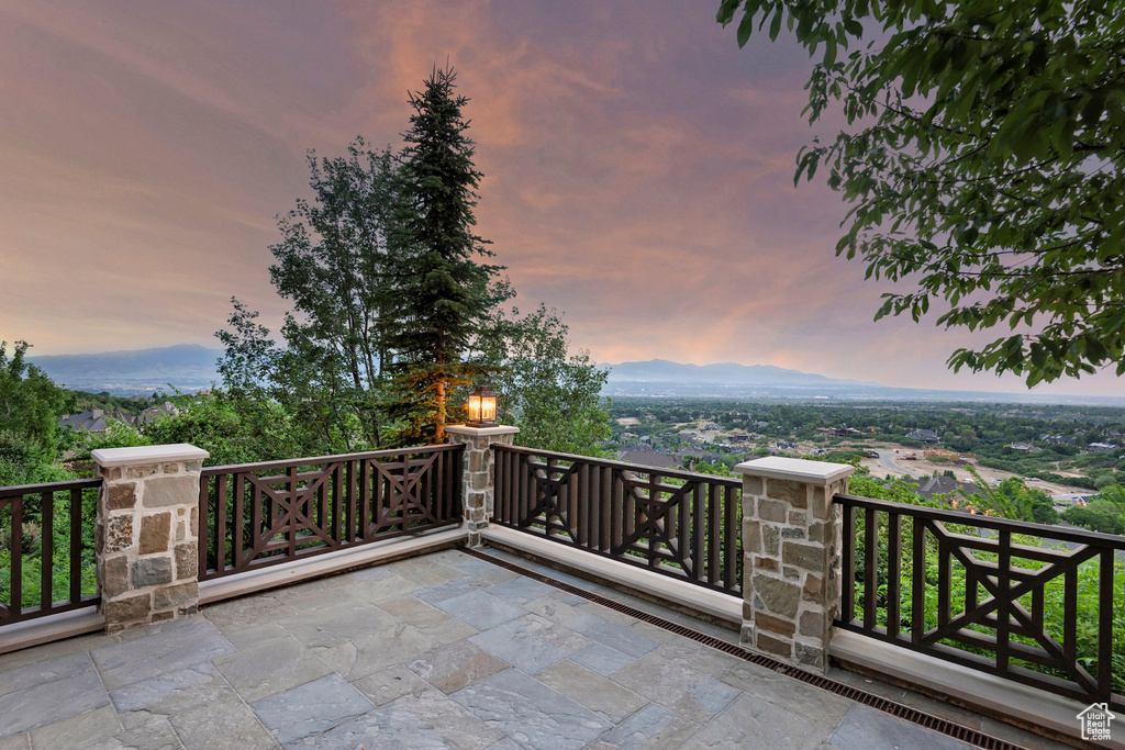 Patio terrace at dusk featuring a mountain view and a balcony