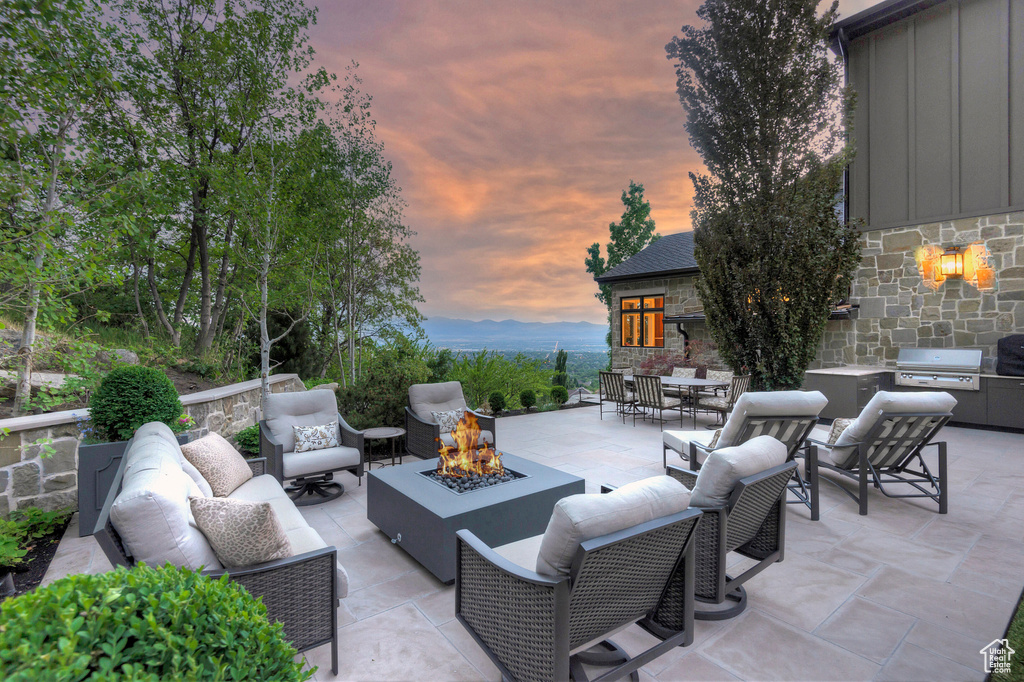 Patio terrace at dusk with a grill and an outdoor hangout area