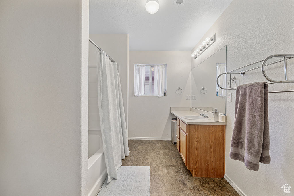 Bathroom with vanity with extensive cabinet space, shower / bath combination with curtain, and tile floors