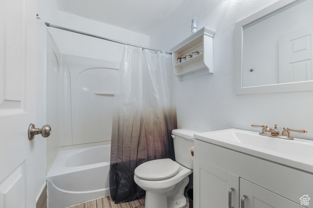 Full bathroom featuring shower / bath combination with curtain, hardwood / wood-style floors, toilet, and large vanity
