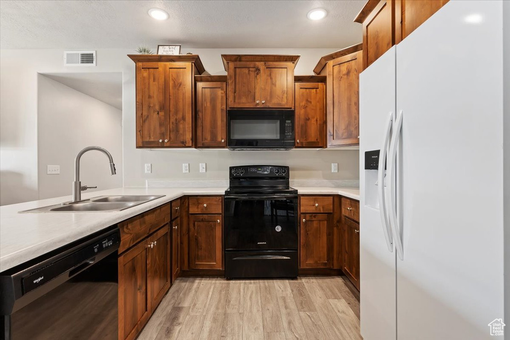 Kitchen featuring sink, light hardwood / wood-style floors, and black appliances