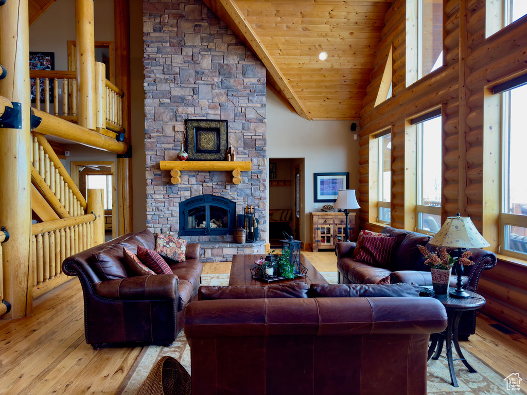 Living room with a fireplace, high vaulted ceiling, wood ceiling, wood-type flooring, and rustic walls