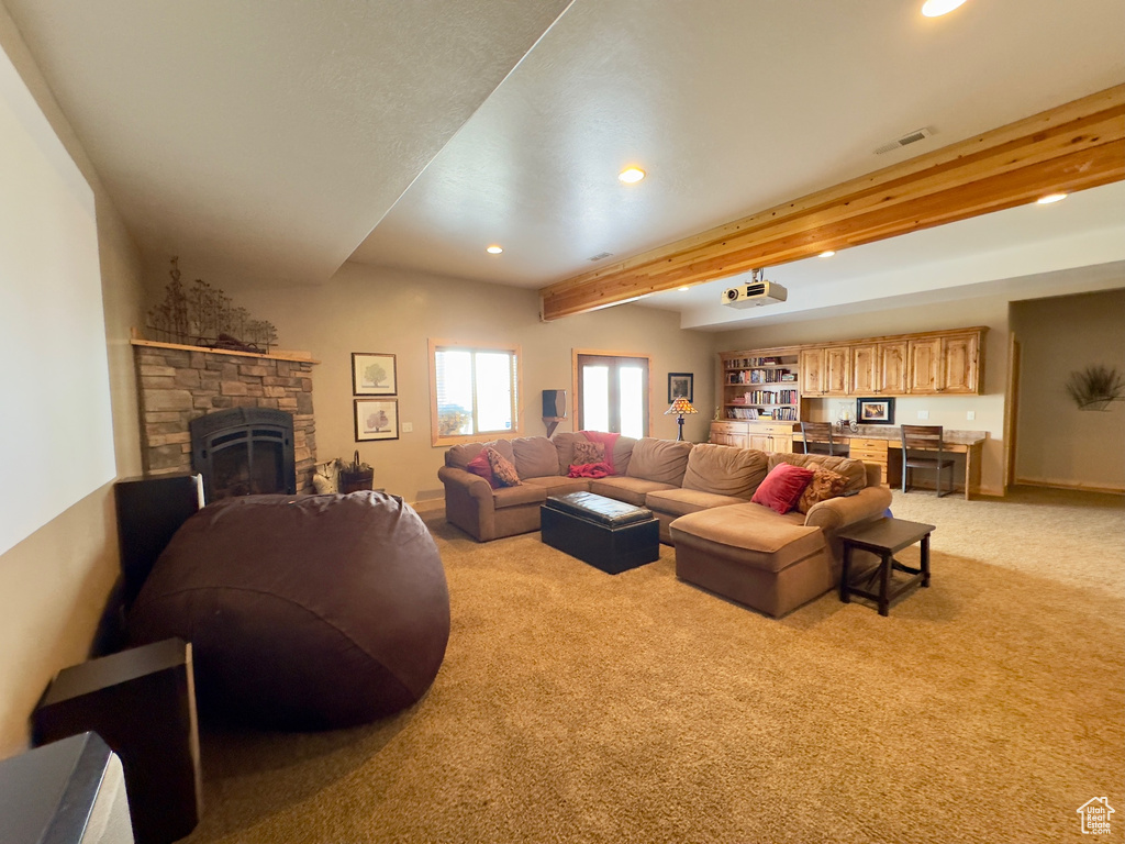 Living room featuring a stone fireplace, light colored carpet, and beamed ceiling