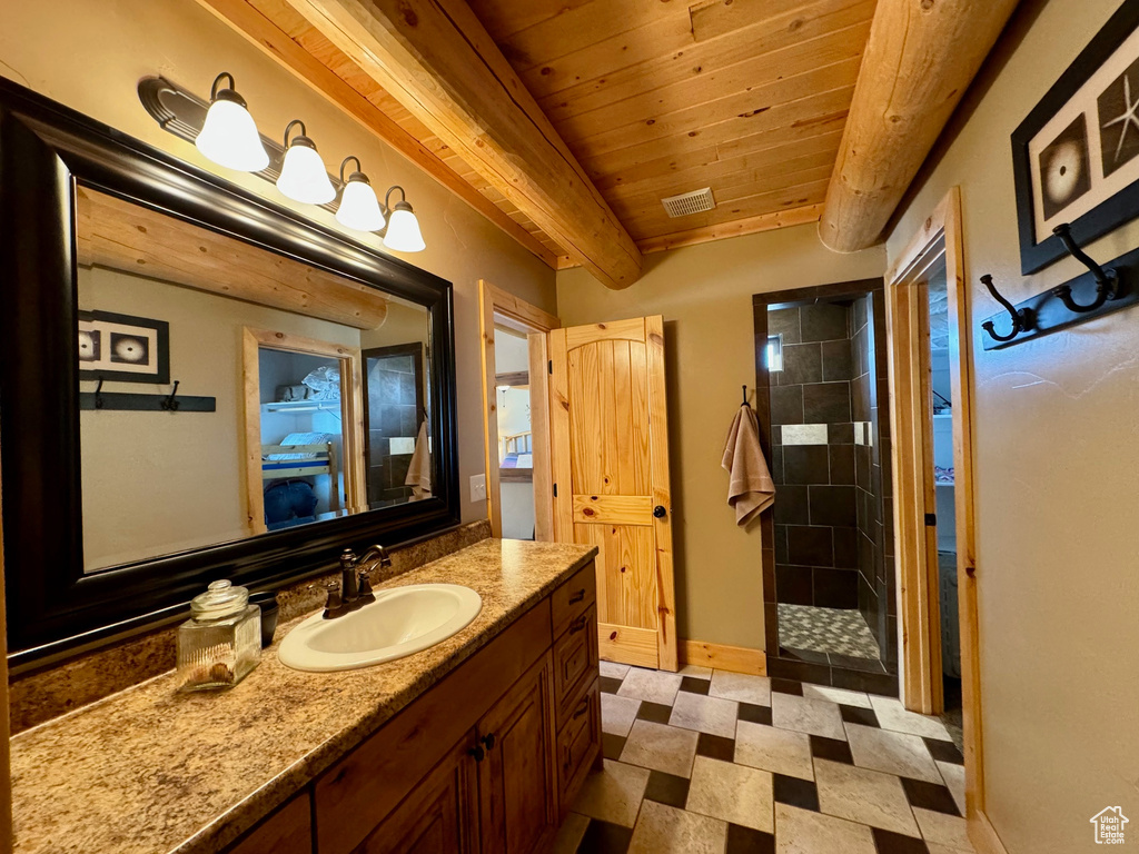 Bathroom featuring vanity, tile flooring, beam ceiling, a tile shower, and wood ceiling