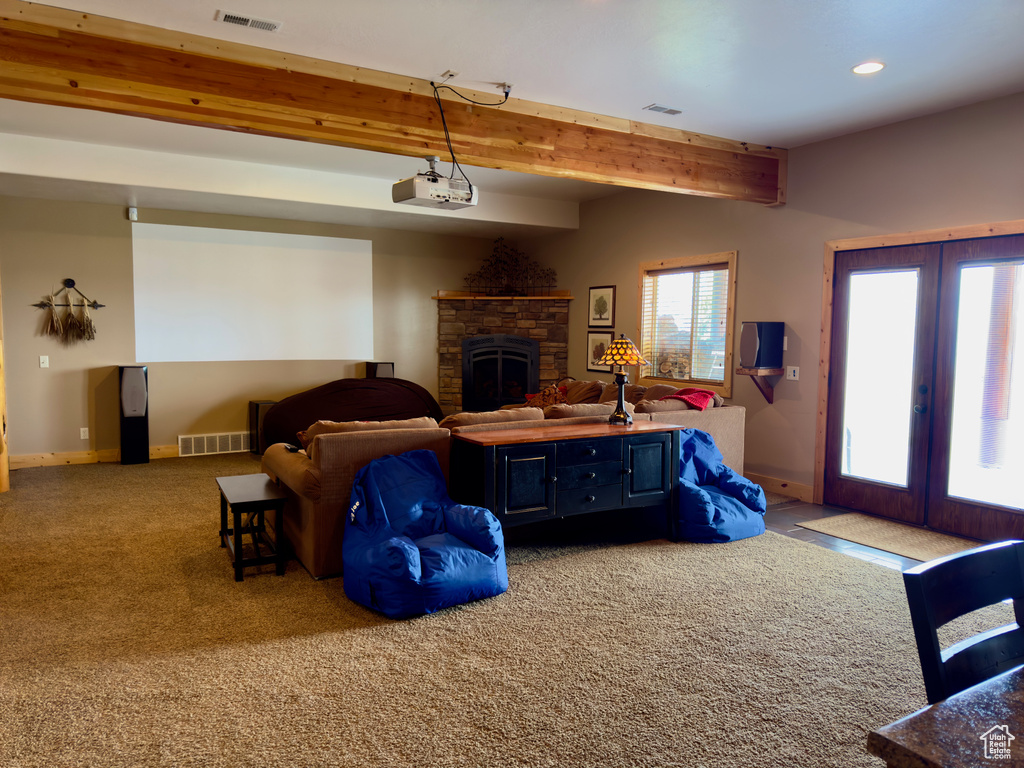 Interior space featuring french doors, beam ceiling, carpet, and a stone fireplace