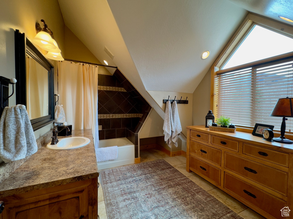 Bathroom featuring lofted ceiling, vanity, and tile flooring