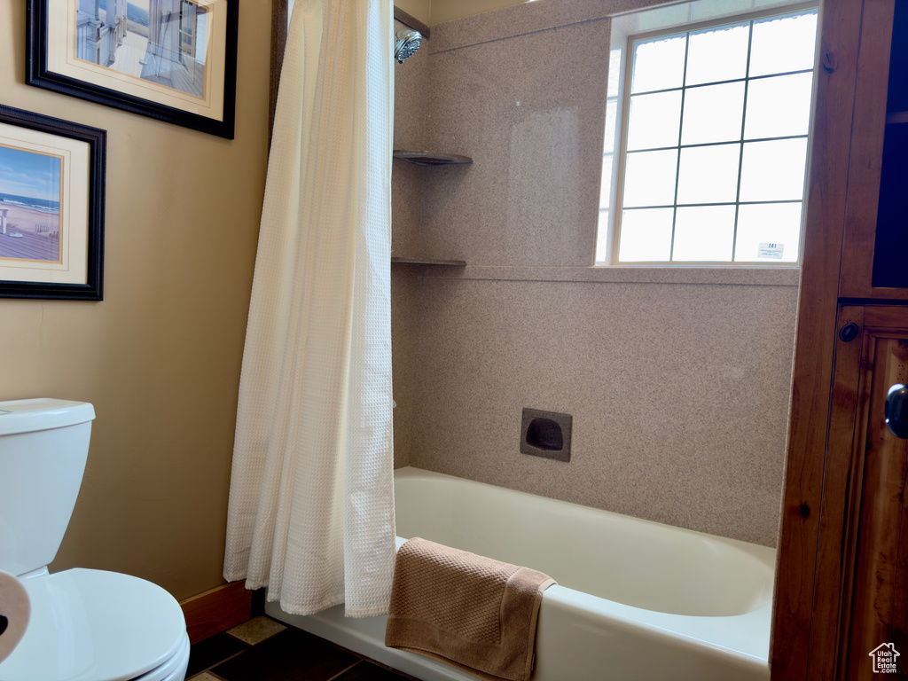 Bathroom featuring tile floors, toilet, and shower / tub combo with curtain