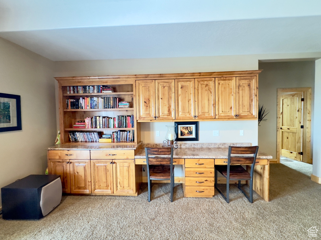 Carpeted home office featuring built in desk