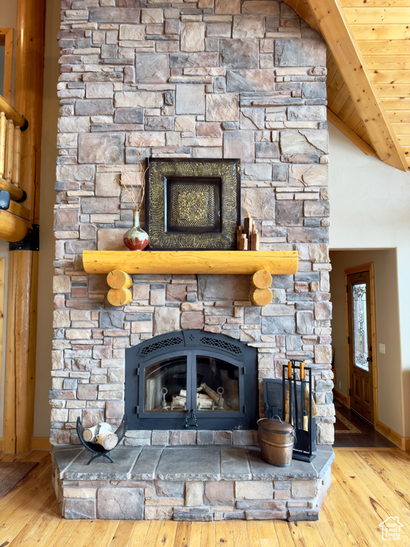 Room details featuring a stone fireplace, wooden ceiling, beamed ceiling, and hardwood / wood-style flooring