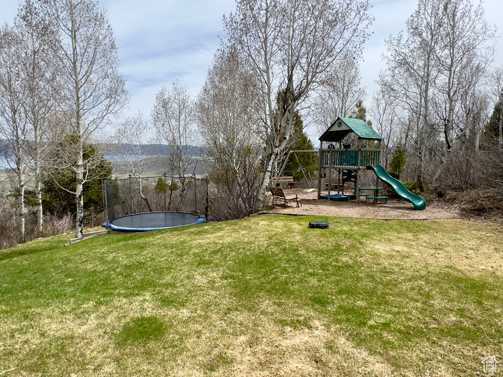 View of yard featuring a trampoline and a playground
