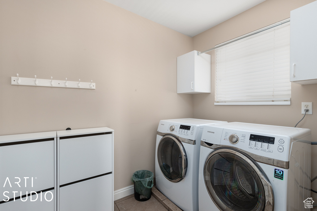 Laundry room with washer and clothes dryer, tile floors, and cabinets