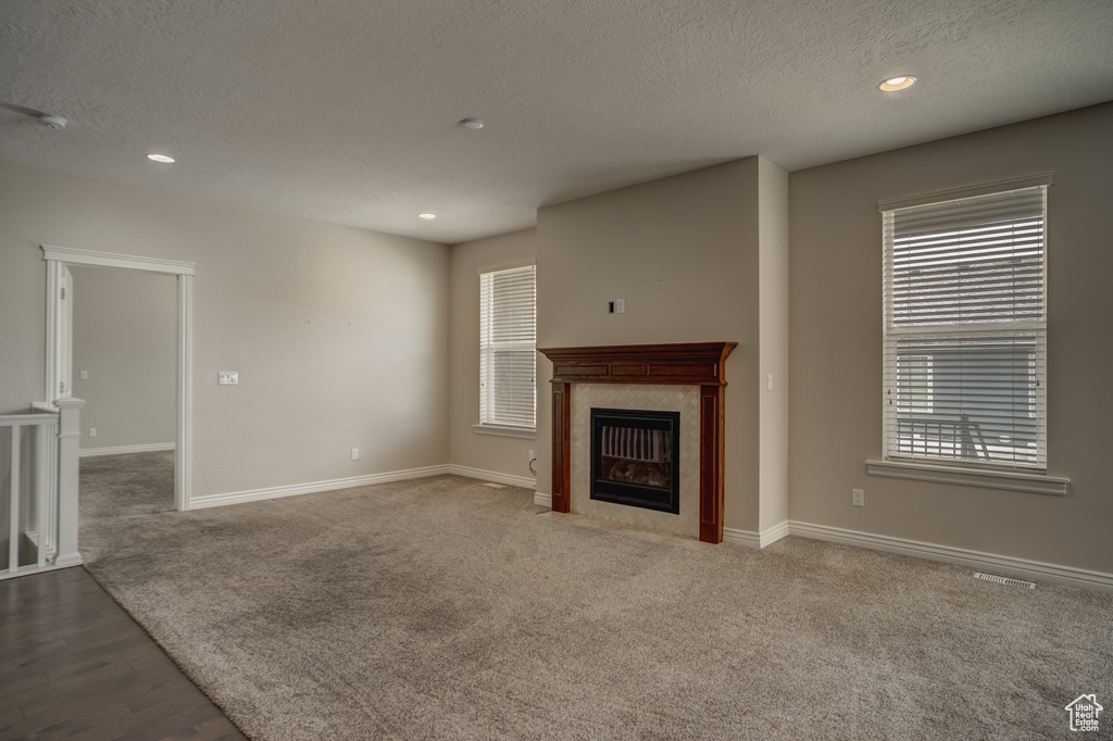 Unfurnished living room with a fireplace, carpet, and plenty of natural light