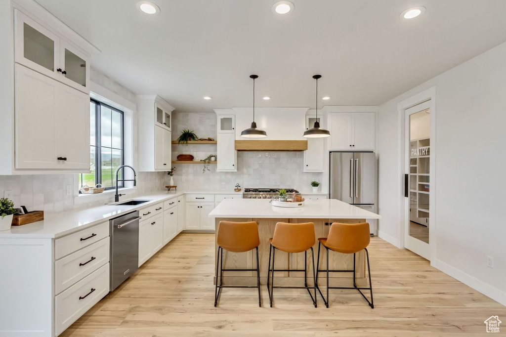 Kitchen featuring white cabinetry, stainless steel appliances, sink, a kitchen island, and light hardwood / wood-style floors
