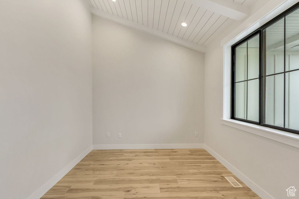 Unfurnished room featuring lofted ceiling with beams and light hardwood / wood-style floors