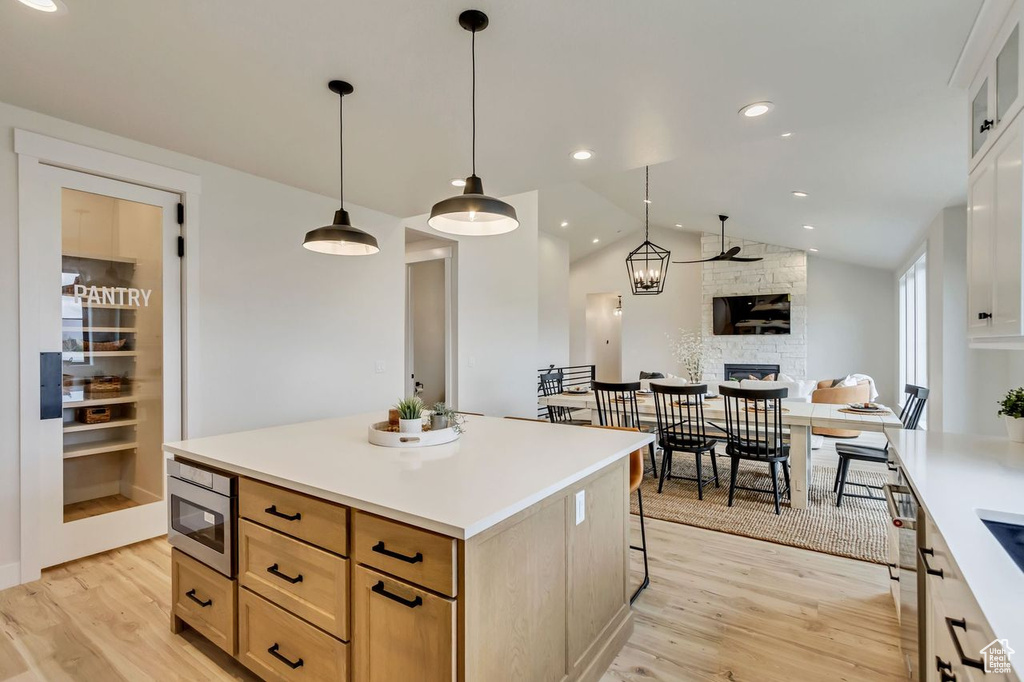 Kitchen featuring light hardwood / wood-style floors, stainless steel microwave, white cabinets, and lofted ceiling