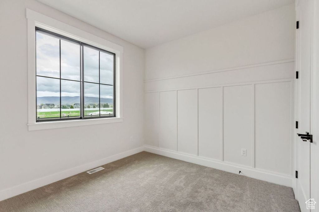 Empty room featuring a mountain view and carpet floors