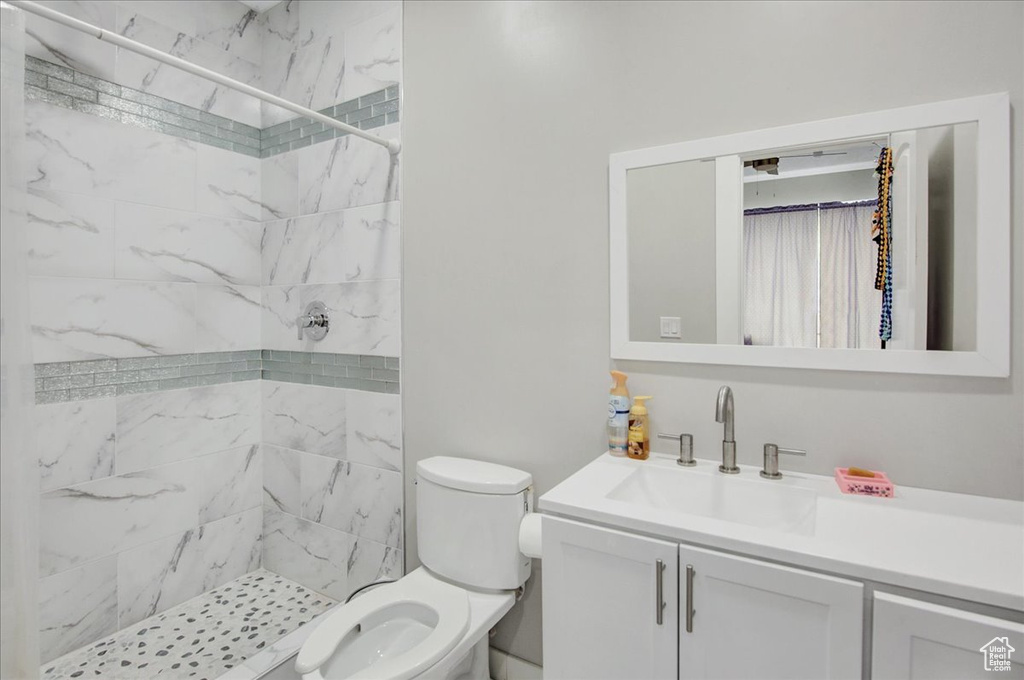 Bathroom featuring vanity, toilet, and tiled shower