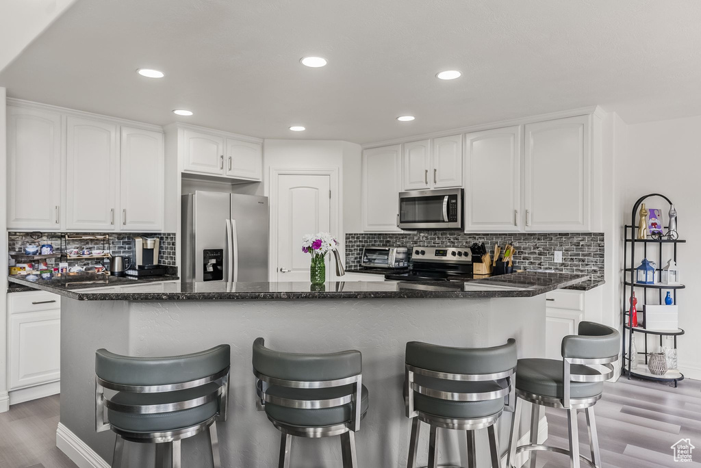 Kitchen featuring backsplash, dark hardwood / wood-style floors, stainless steel appliances, and white cabinetry