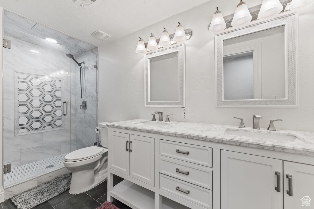 Bathroom featuring walk in shower, toilet, double vanity, and tile flooring