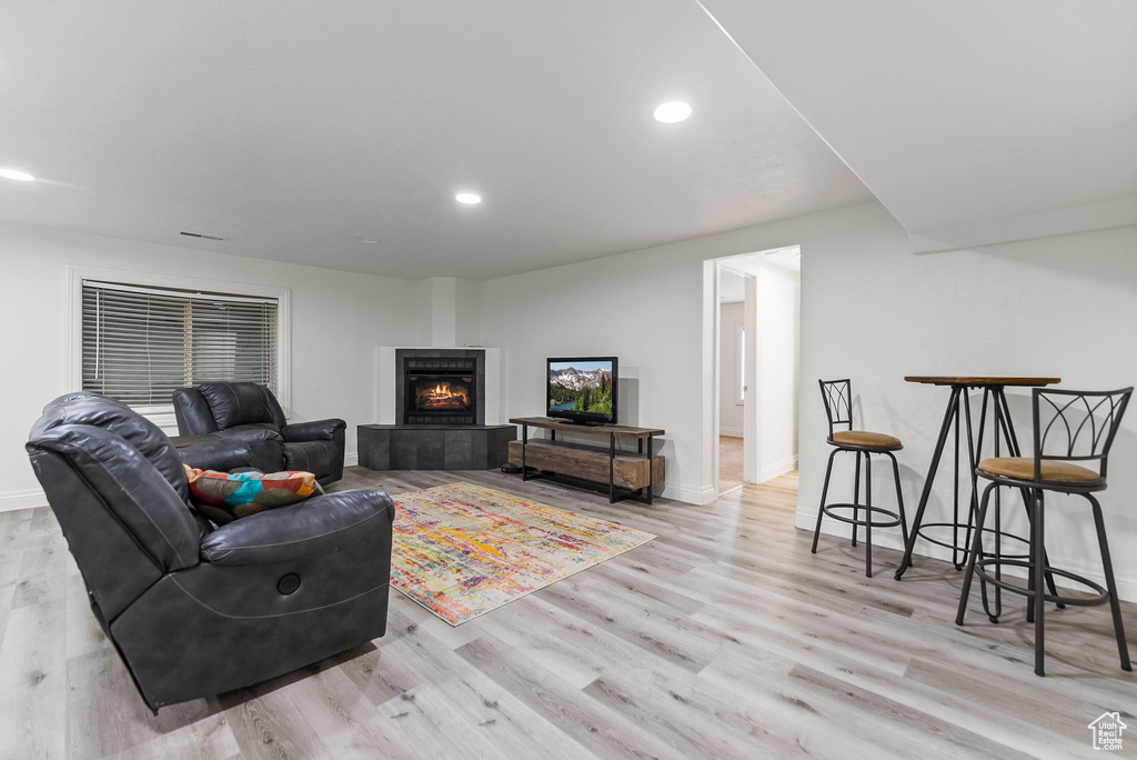 Living room with a tiled fireplace and light hardwood / wood-style floors