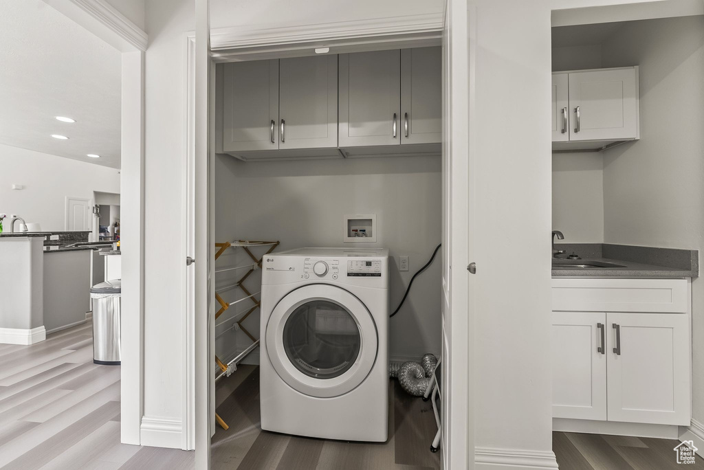 Laundry room with washer / dryer, light hardwood / wood-style flooring, cabinets, and sink