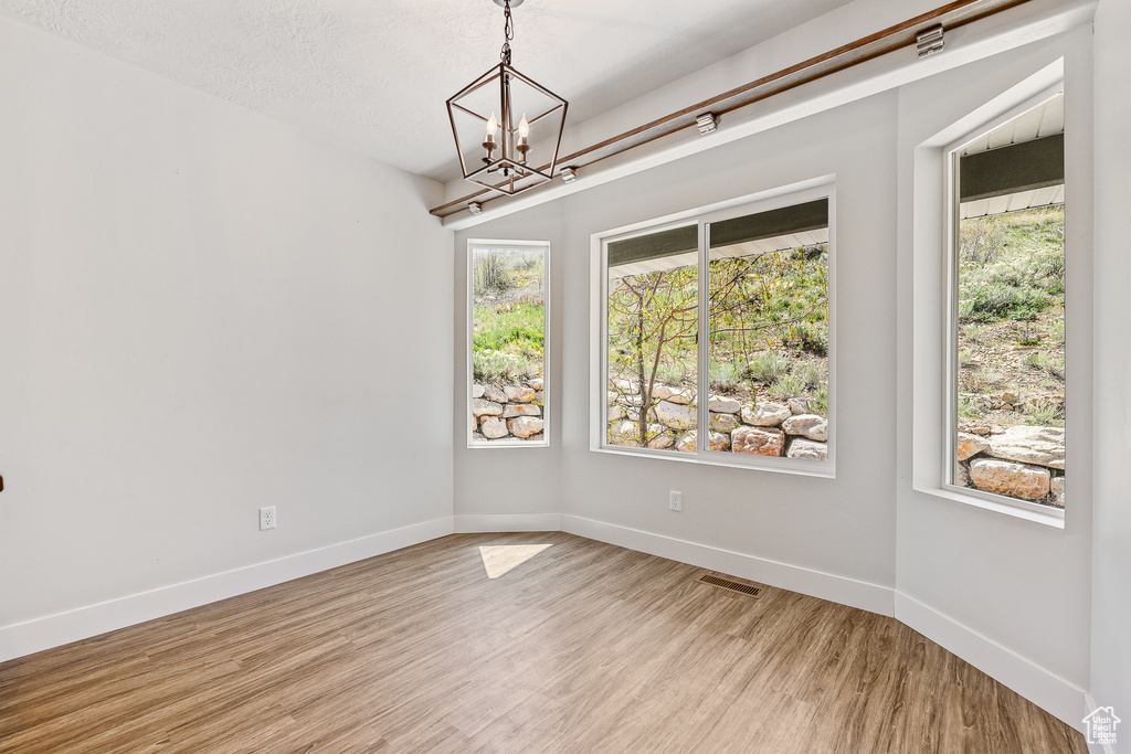 Empty room with light hardwood / wood-style floors and a chandelier