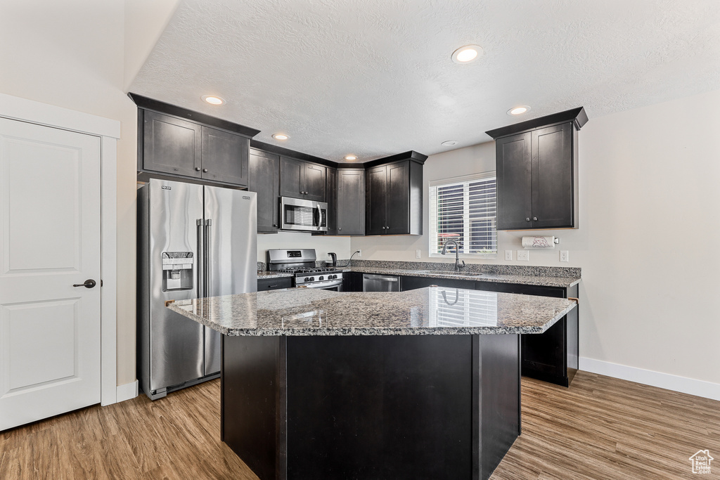 Kitchen with a kitchen island, stainless steel appliances, sink, and light wood-type flooring