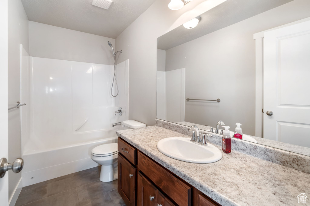 Full bathroom with tile flooring, oversized vanity, toilet, and shower / washtub combination