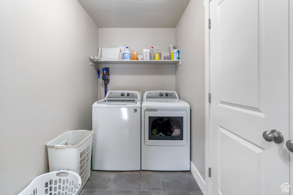 Clothes washing area with washer and clothes dryer and dark tile flooring