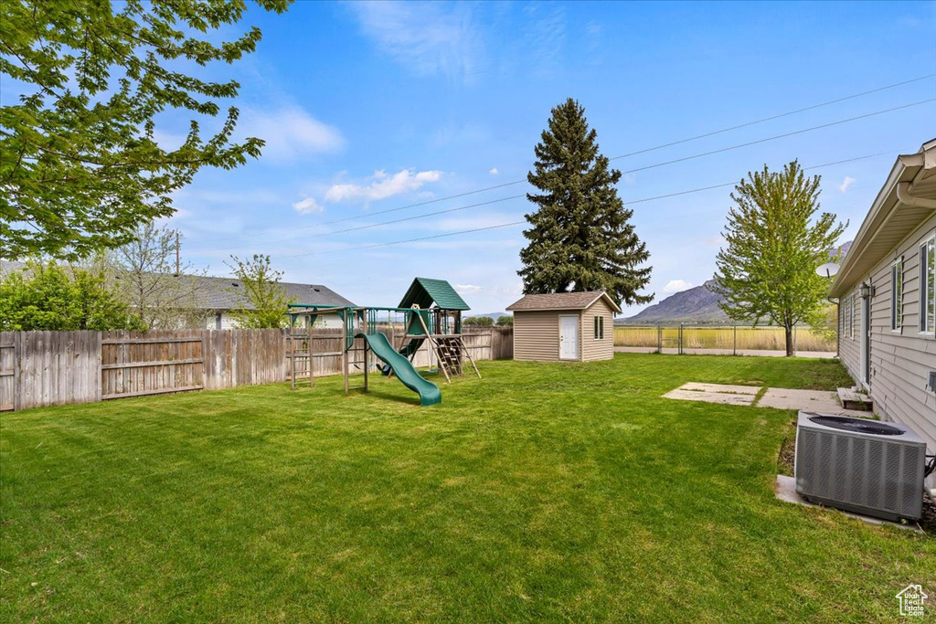 View of yard featuring a mountain view, a playground, central AC, and a shed