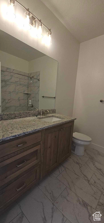 Bathroom featuring tile flooring, vanity, toilet, and a textured ceiling