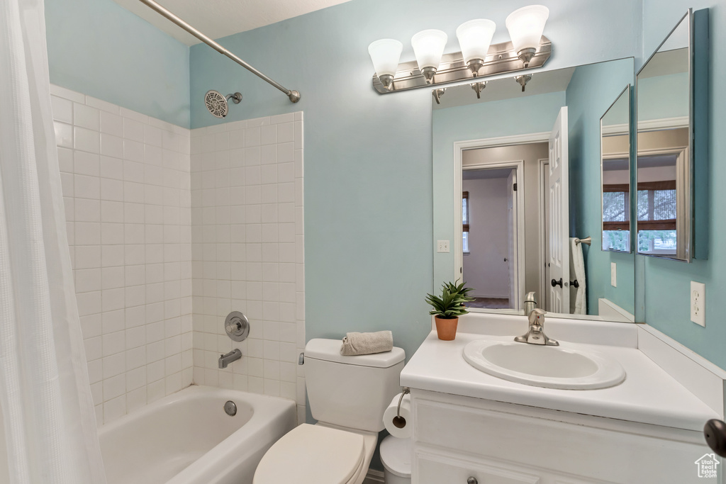 Full bathroom featuring oversized vanity, toilet, and shower / tub combo with curtain