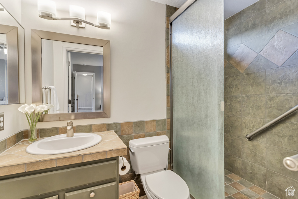 Bathroom featuring a shower with door, toilet, and oversized vanity