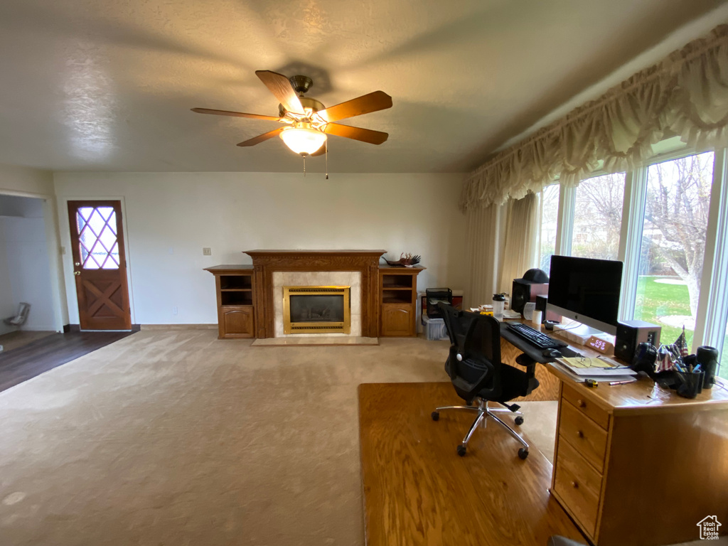Carpeted home office with ceiling fan and a high end fireplace