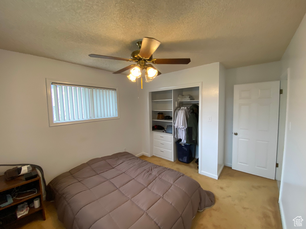 Carpeted bedroom featuring a closet, ceiling fan, and a textured ceiling
