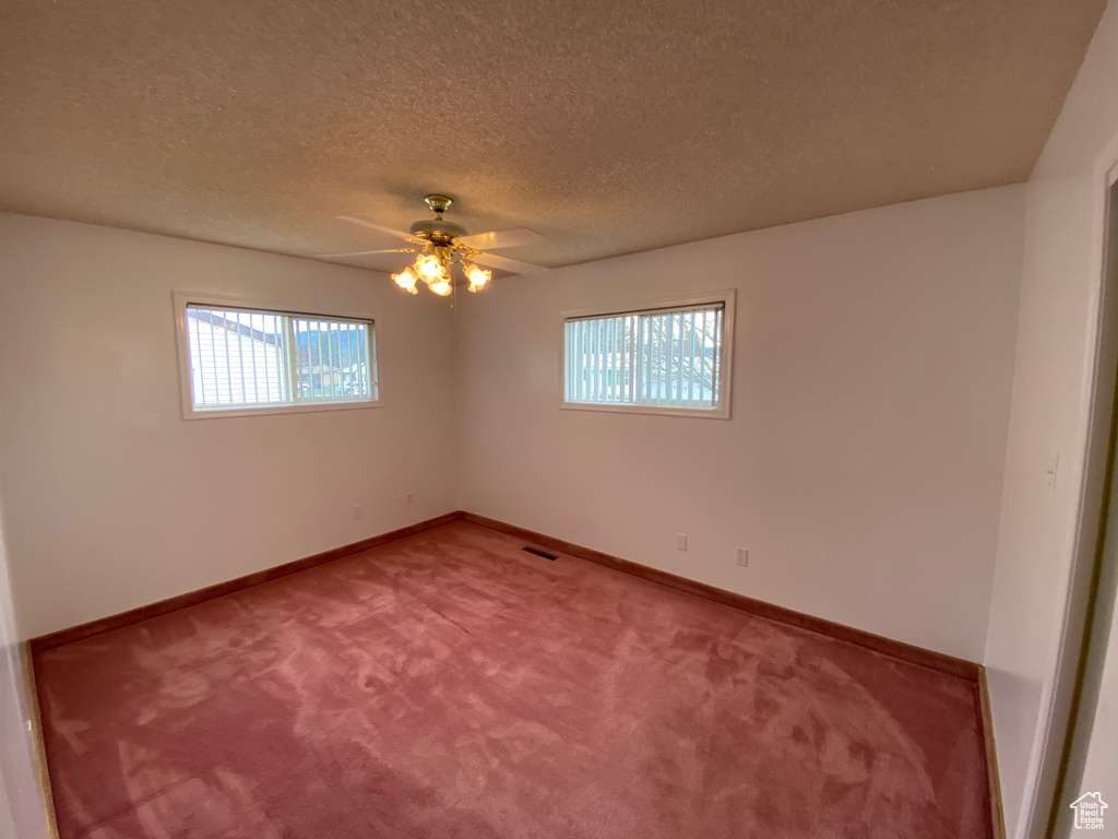 Carpeted empty room with ceiling fan and a textured ceiling