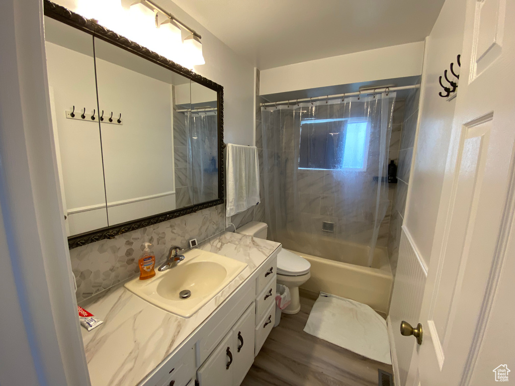 Full bathroom featuring shower / bathtub combination with curtain, wood-type flooring, toilet, and large vanity