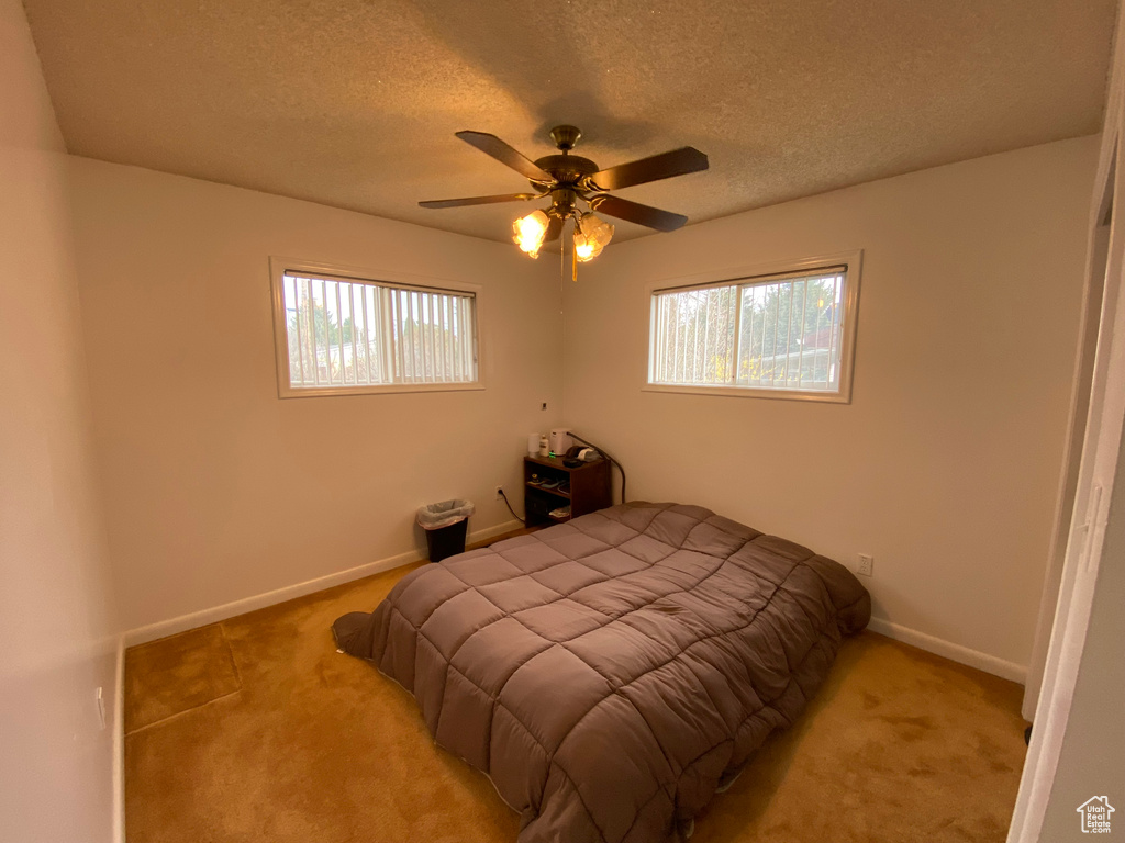 Bedroom featuring a textured ceiling, ceiling fan, and carpet