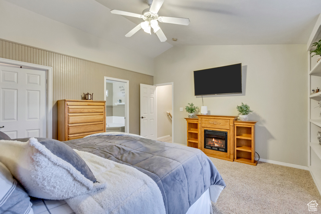 Carpeted bedroom featuring vaulted ceiling, ceiling fan, and ensuite bath