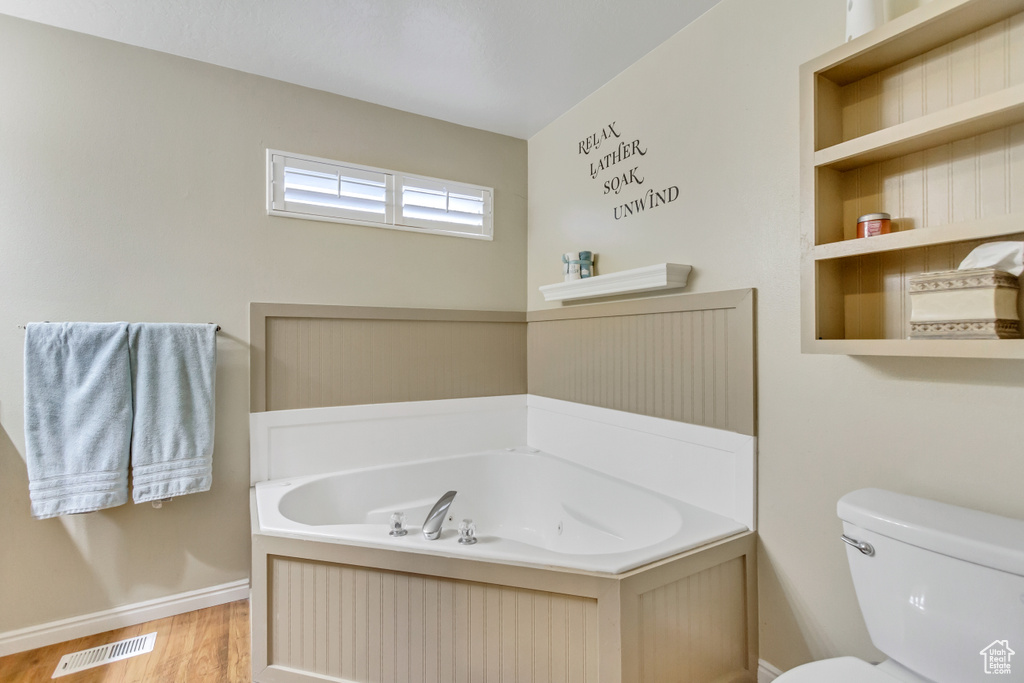 Bathroom featuring hardwood / wood-style flooring, built in features, toilet, and a bathtub