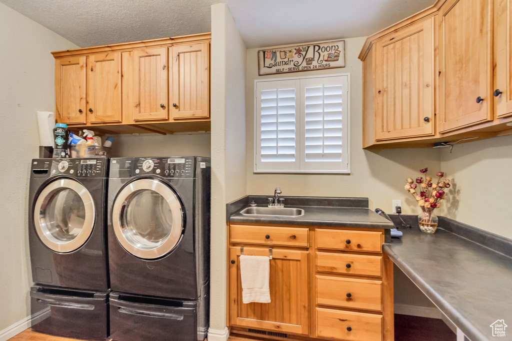 Laundry room featuring a textured ceiling, separate washer and dryer, cabinets, and sink