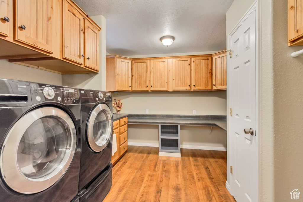 Clothes washing area featuring cabinets, separate washer and dryer, and light wood-type flooring