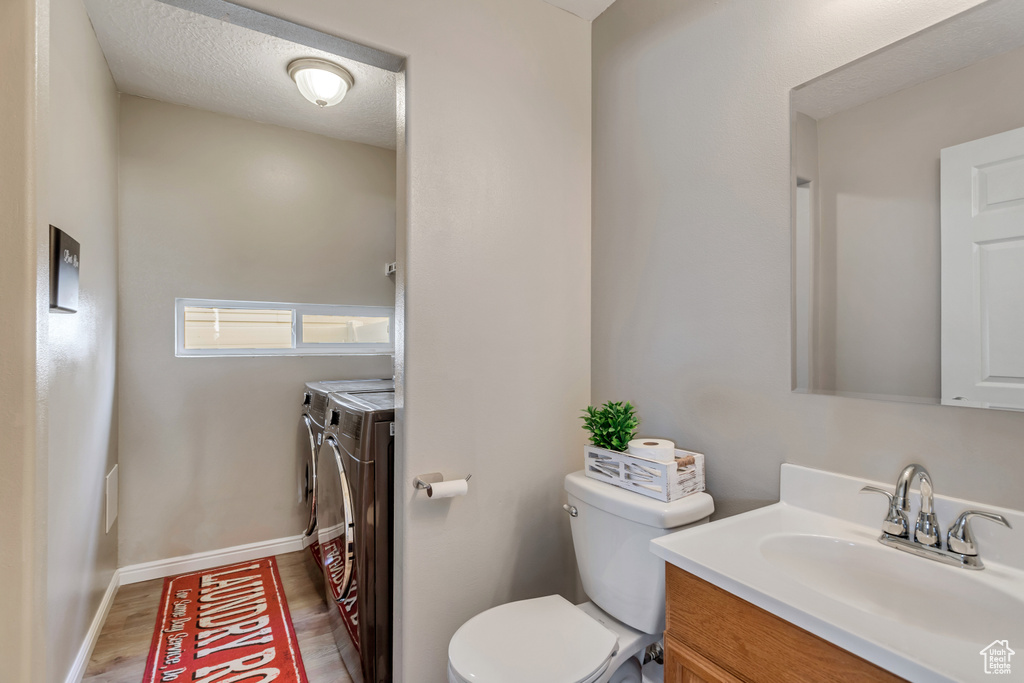 Bathroom with toilet, a textured ceiling, vanity, hardwood / wood-style flooring, and washer and clothes dryer