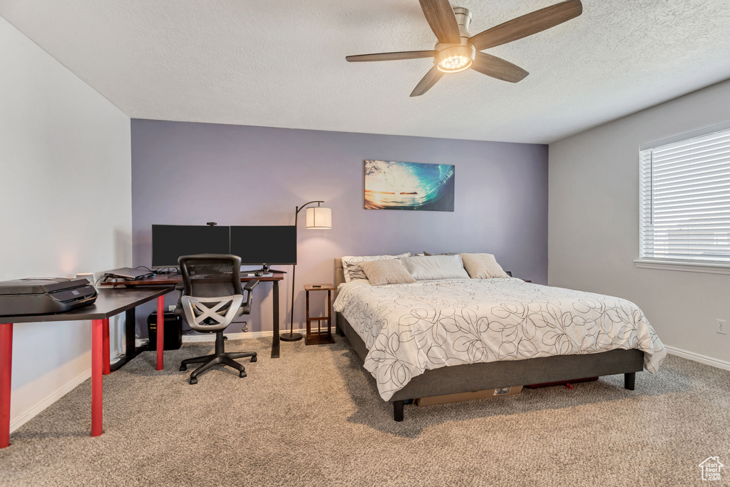 Bedroom with ceiling fan, carpet floors, and a textured ceiling